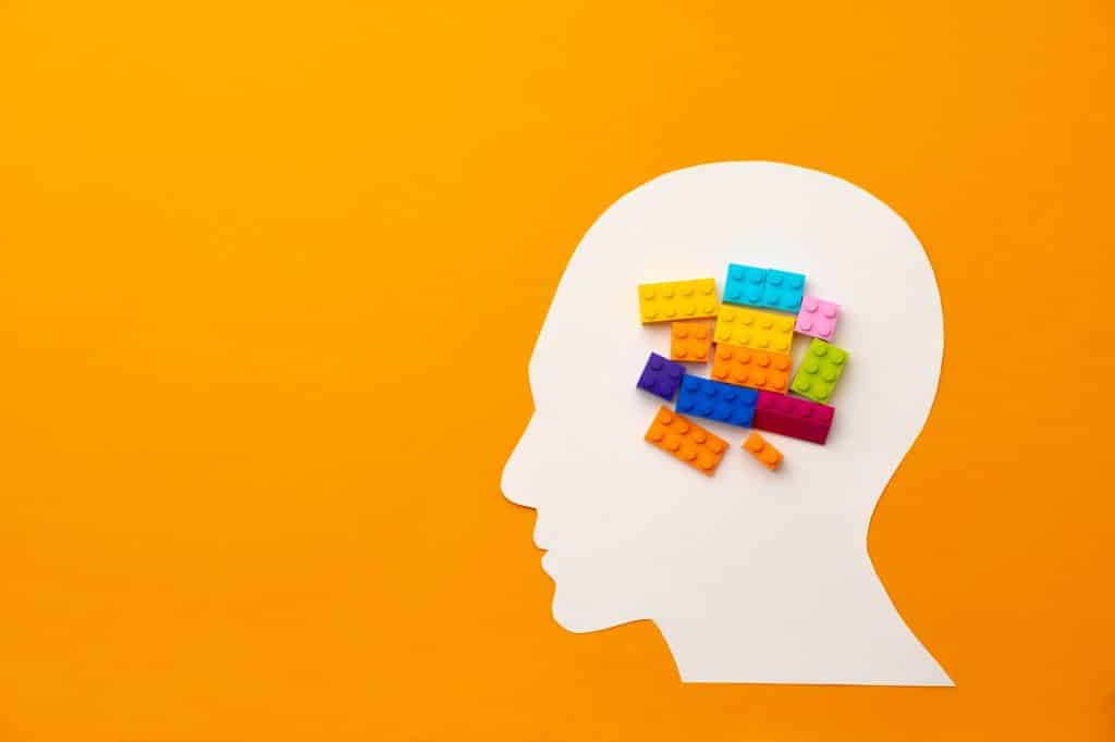 Papercut head silhouette with toy constructor pieces on yellow background