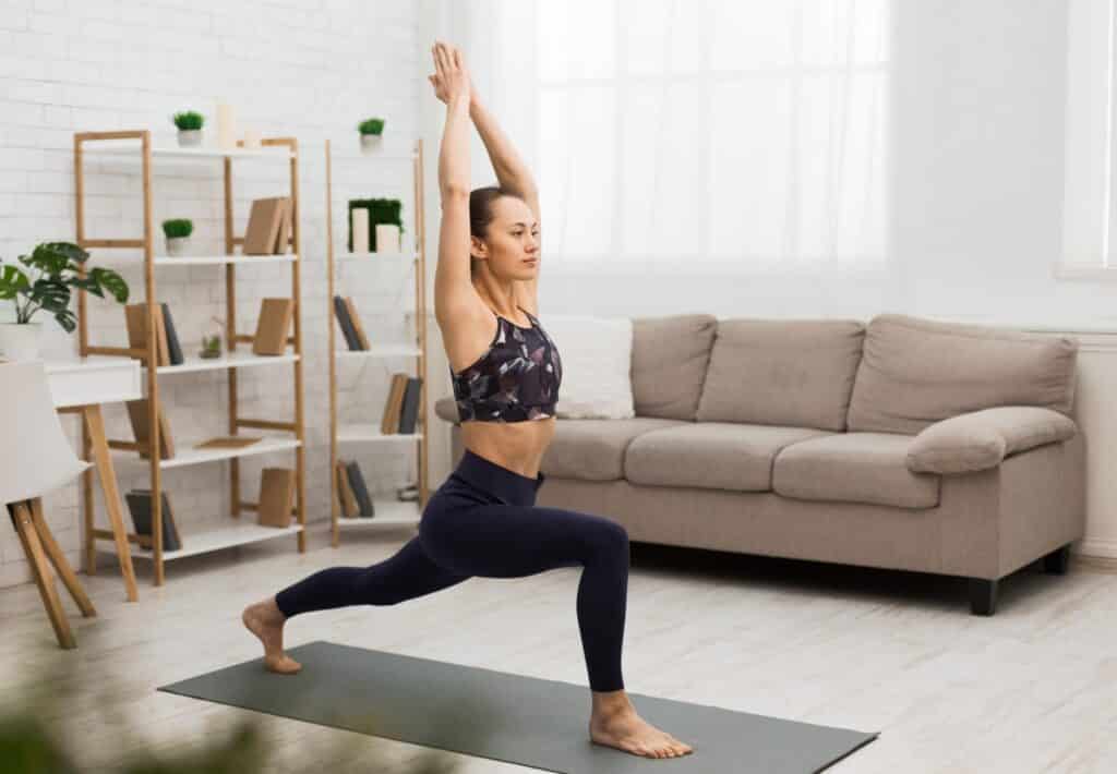 Athletic woman doing yoga, stretching exercise at home