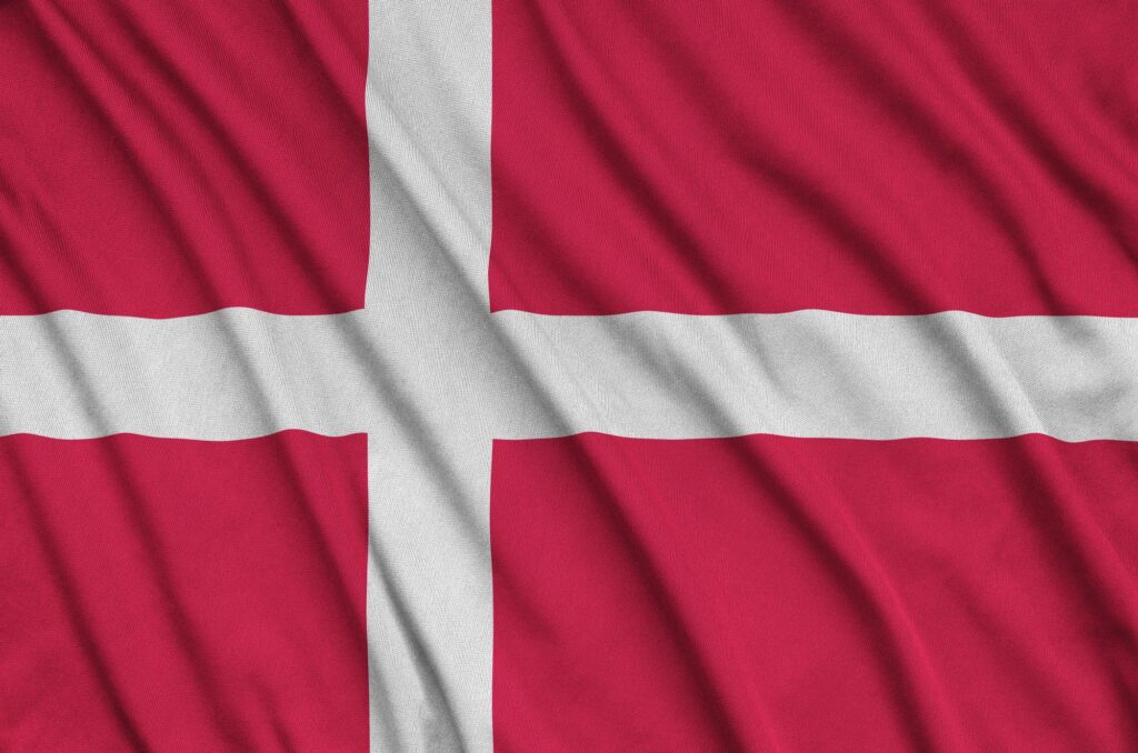 Denmark flag is depicted on a sports cloth fabric with many folds. Sport team waving banner