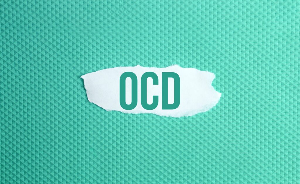 Obsessive–compulsive disorder. a torn paper written with inscription OCD on a green background